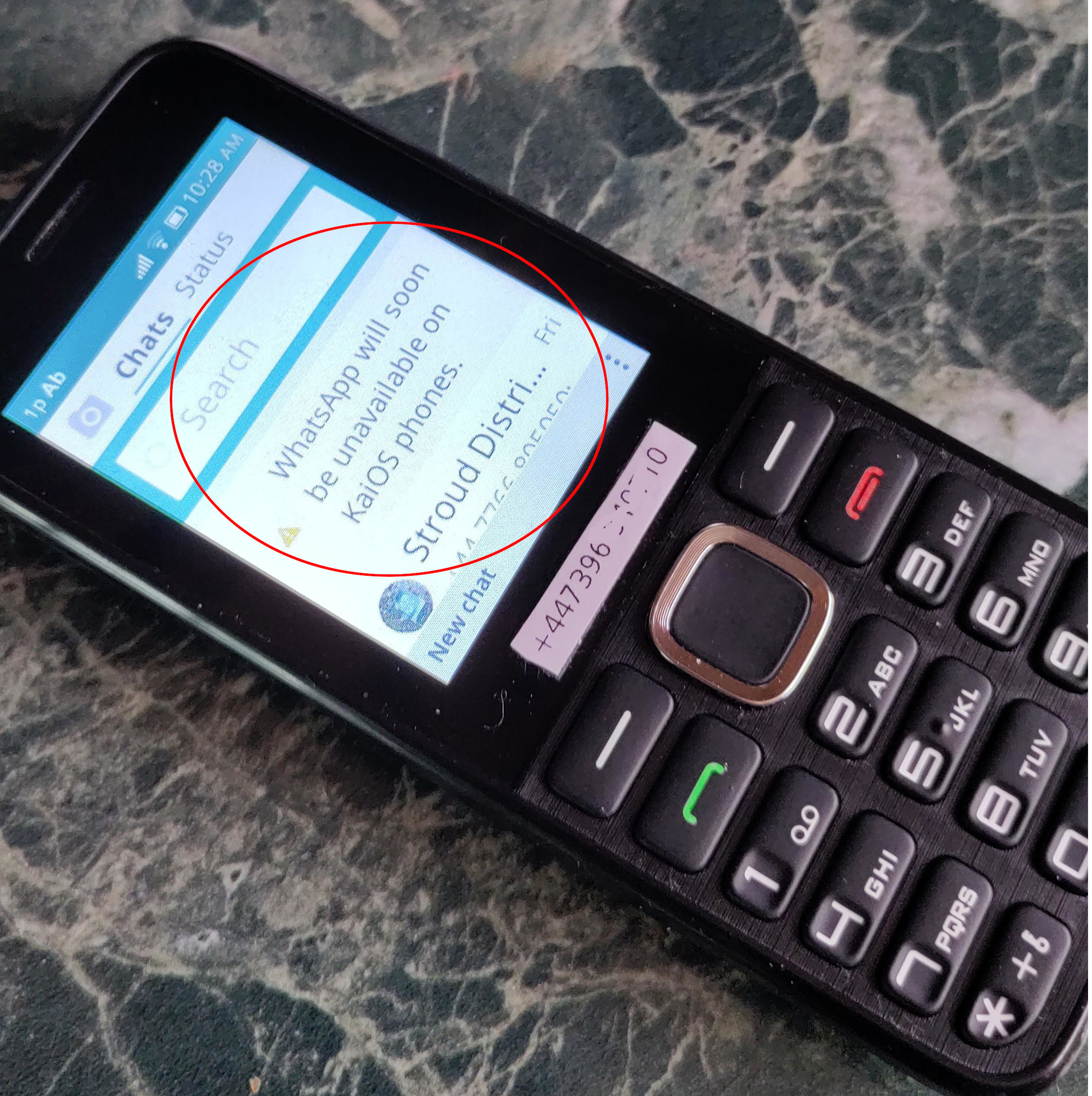 A KaiOS mobile phone displaying a warning message that WhatsApp support is being discontinued